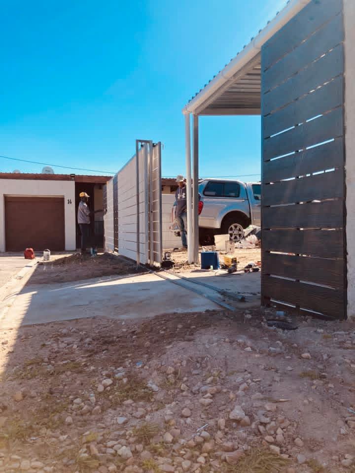 T One Steel Projects team installing steel gate panels on site with tools and a bakkie alongside